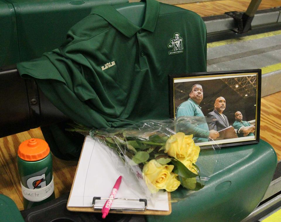 A memorial to the late Illya McGee, pictured in framed photograph, left, next to head coach Dru Joyce II and fellow assistant coach Tron Rhoden, on the team bench during the court dedication ceremony to Joyce at LeBron James Arena at St. Vincent St. Mary High School Sunday in Akron. It was announced at the ceremony that the boys locker room will be dedicated in McGee's name.