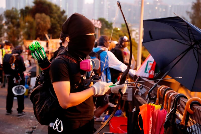 FILE PHOTO: An anti-government protester holds a bow as he stands at a makeshift gate during a standoff with riot police at the Chinese University of Hong Kong, Hong Kong, China