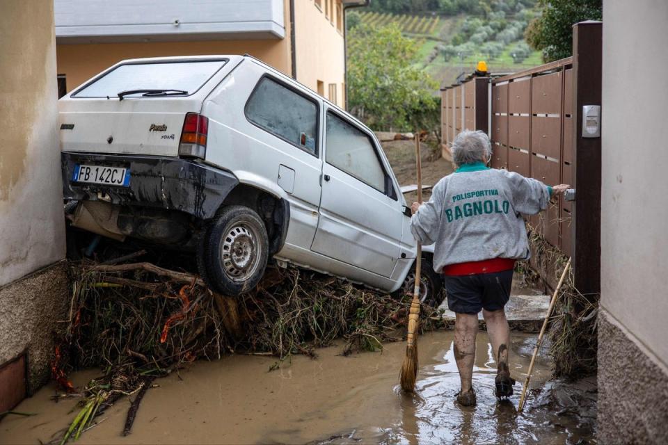 A woman tries to clean the mud in Montemurlo near Prato, Italy, on Friday, after heavy rain (AFP via Getty Images)