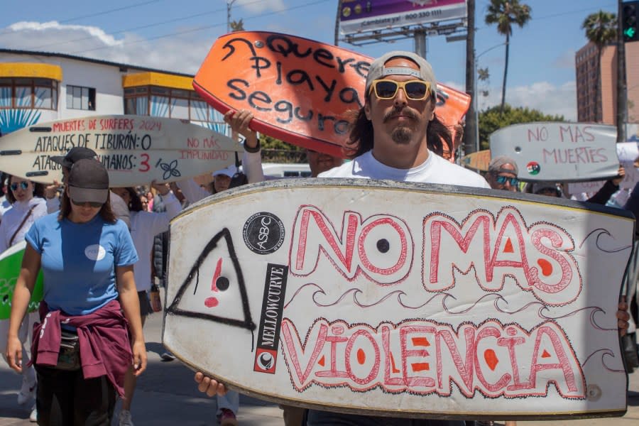 A demonstrator holding a bodyboard written in Spanish ” No more violence” protests the disappearance of foreign surfers in Ensenada, Mexico, Sunday, May 5, 2024. Mexican authorities said Friday that three bodies were recovered in an area of Baja California near where two Australians and an American went missing last weekend during an apparent camping and surfing trip. (AP Photo/Karen Castaneda)