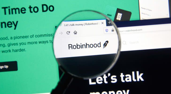 A magnifying glass zooms in on the website for Robinhood (HOOD).