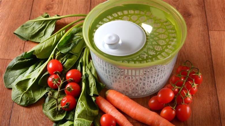 Empty salad spinner next to vegetables  