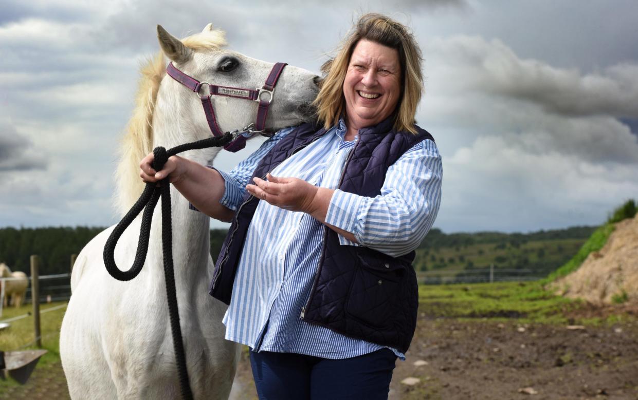 Horse and owner stand in a muddy field with a lowering sky