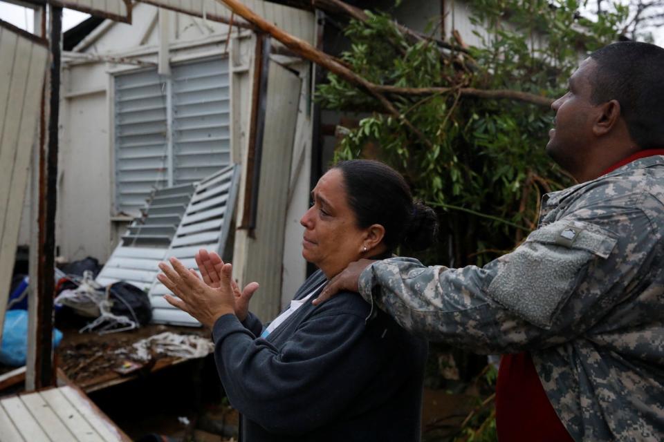 a man comforts a distraught woman surveying a destroyed home after hurricane maria in puerto rico