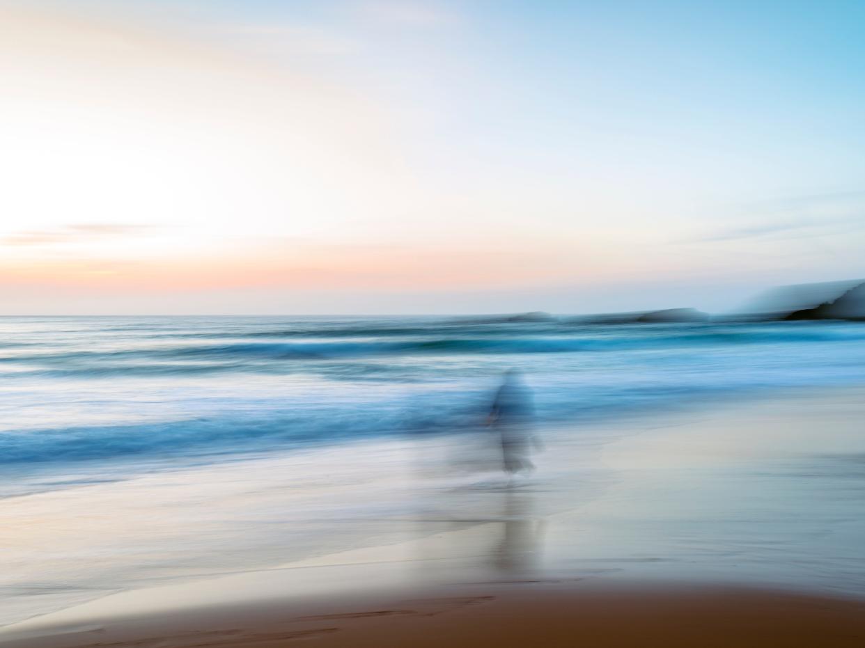 Blurred person walking on beach at sunset