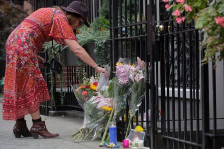 A woman leaves a card and flowers at a memorial outside the home of singer and producer Ric Ocasek following his death in New York