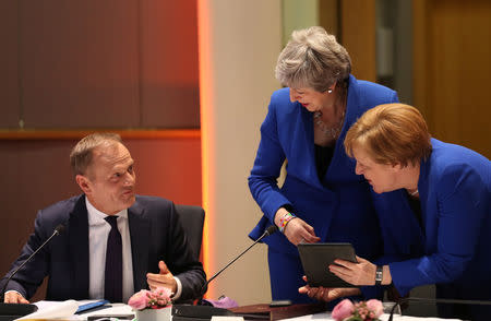 Britain's Prime Minister Theresa May and Germany's Chancellor Angela Merkel look at a tablet next to European Council President Donald Tusk, ahead of a European Council meeting on Brexit at the Europa Building at the European Parliament in Brussels, Belgium April 10, 2019. Kenzo Tribouillard/Pool via REUTERS