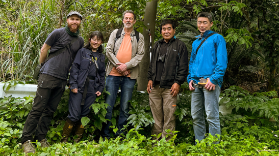 The five members of the research team, dressed in outdoor clothing in a forested area