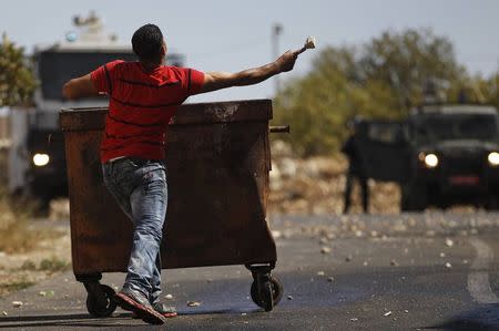 A Palestinian man throws a stone towards Israeli troops during clashes following the funeral of Issa al Qitri, in West Bank city of Ramallah September 10, 2014. REUTERS/Mohamad Torokman