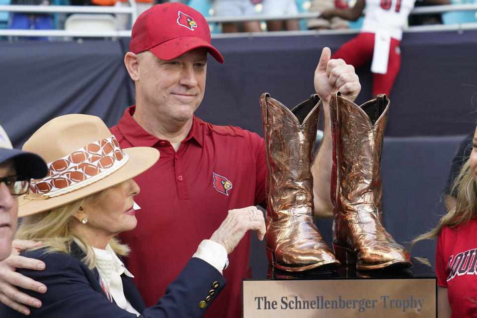 Beverlee Schnellenberger, left, presents the Schnellenberger Trophy to Louisville head coach Jeff Brohm after an NCAA college football game between Miami and Louisville, Saturday, Nov. 18, 2023, in Miami Gardens, Fla. The trophy is named after Schnellenberger's late husband, former Louisville and Miami head coach Howard Schnellenberger. (AP Photo/Wilfredo Lee)