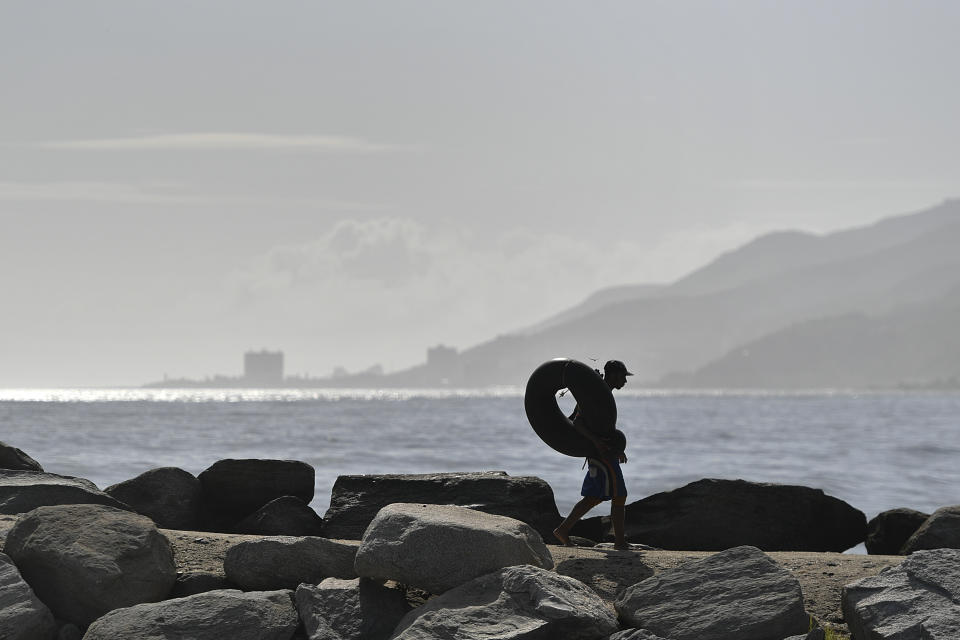 Edward Murat, de 20 años, carga un neumático por la playa y que usa para pescar en mar abierto frente a Playa Escondida, en La Guaira, Venezuela, el viernes 14 de agosto de 2020. La pandemia de coronavirus ha obligado a cada vez más personas en la ciudad costera a pescar en alta mar con cámaras neumáticas recuperadas de la basura. (Foto AP/Matias Delacroix)