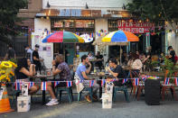 FILE - In this June 26, 2020, file photo, diners eat al fresco due to COVID-19 concerns in the West Village in New York. As coronavirus rages out of control in other parts of the U.S., New York is offering an example after taming the nation’s deadliest outbreak this spring — but also trying to prepare in case another surge comes. (AP Photo/John Minchillo)