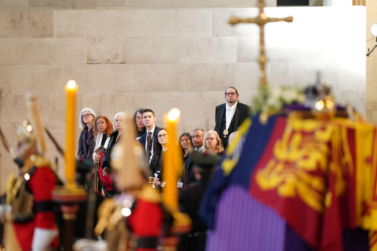 Members of the public file past the coffin of Queen Elizabeth II, draped in the Royal Standard with the Imperial State Crown and the Sovereign's orb and sceptre, lying in state on the catafalque in Westminster Hall