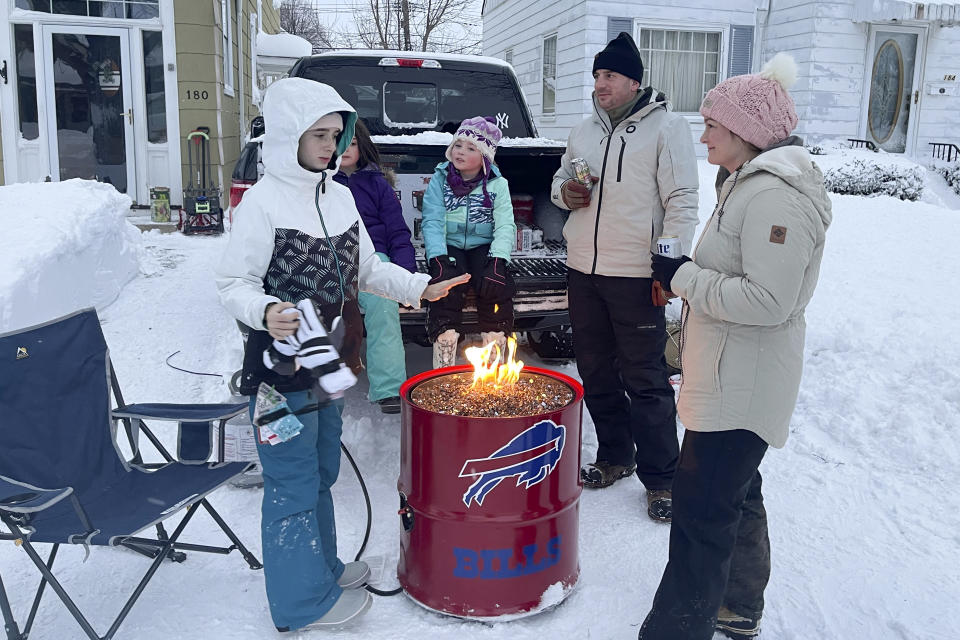 A group of neighbors gather around a fire pit on Culver Road after clearing snow in Buffalo, N.Y., Monday, Dec. 26, 2022. The region is digging out from a pre-Christmas blizzard that delivered hurricane-force winds and more than 4 feet of snow. (AP Photo/Carolyn Thompson)