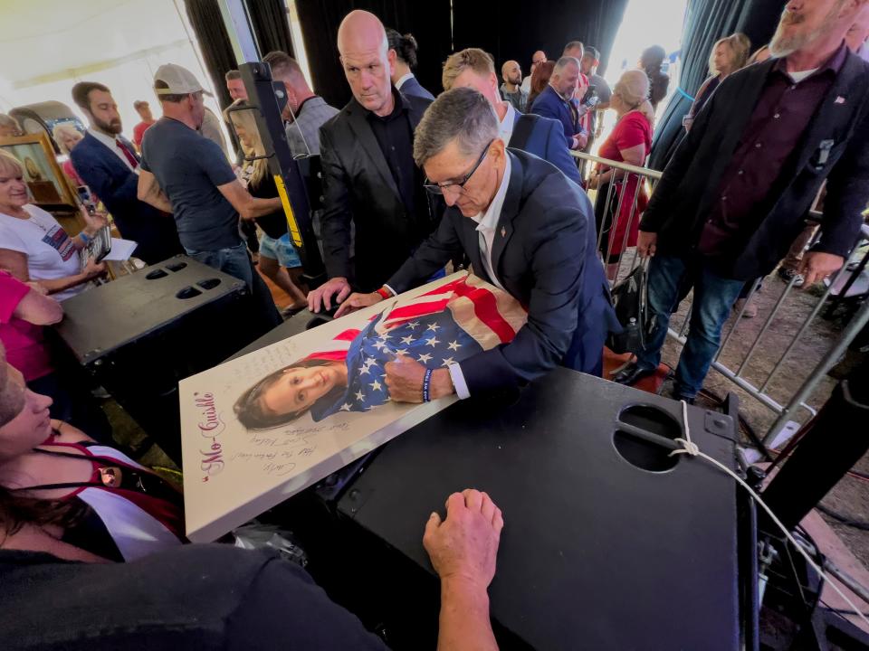 Michael Flynn, a retired three-star general who served as President Donald Trumpâ€™s national security advisor, autographs a picture of a girl wrapped in an American flag during the ReAwaken America Tour at Cornerstone Church in Batavia, N.Y., Friday, Aug. 12, 2022. Flynn, one of the tourâ€™s founders and its star, warned the crowd that they were in the midst of a â€œspiritual warâ€ and urges people to get involved in local politics." (AP Photo/Carolyn Kaster)