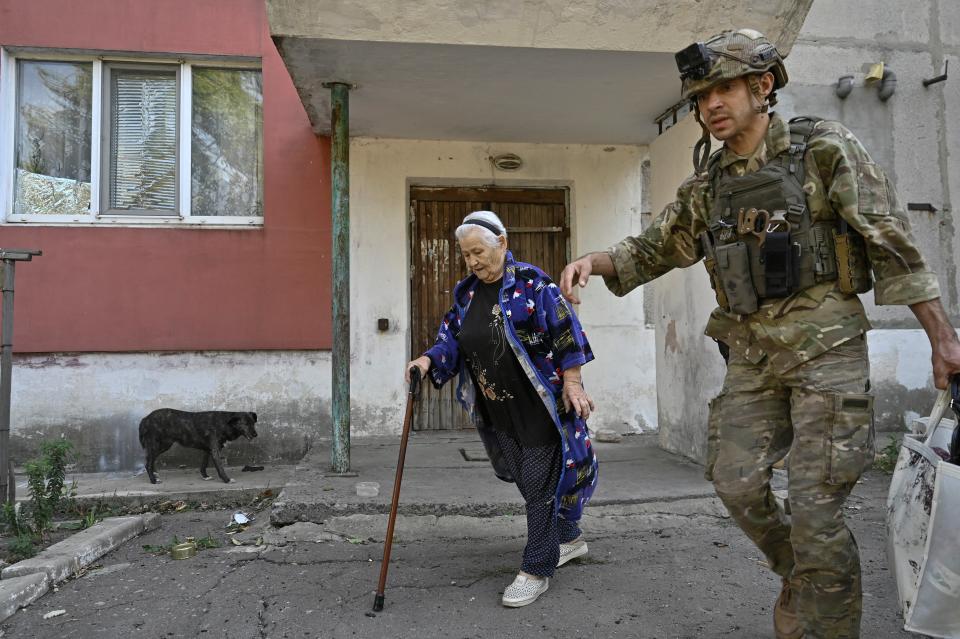 A police officer assists a civilian woman during an evacuation from outskirts of the Kurakhove town (REUTERS)