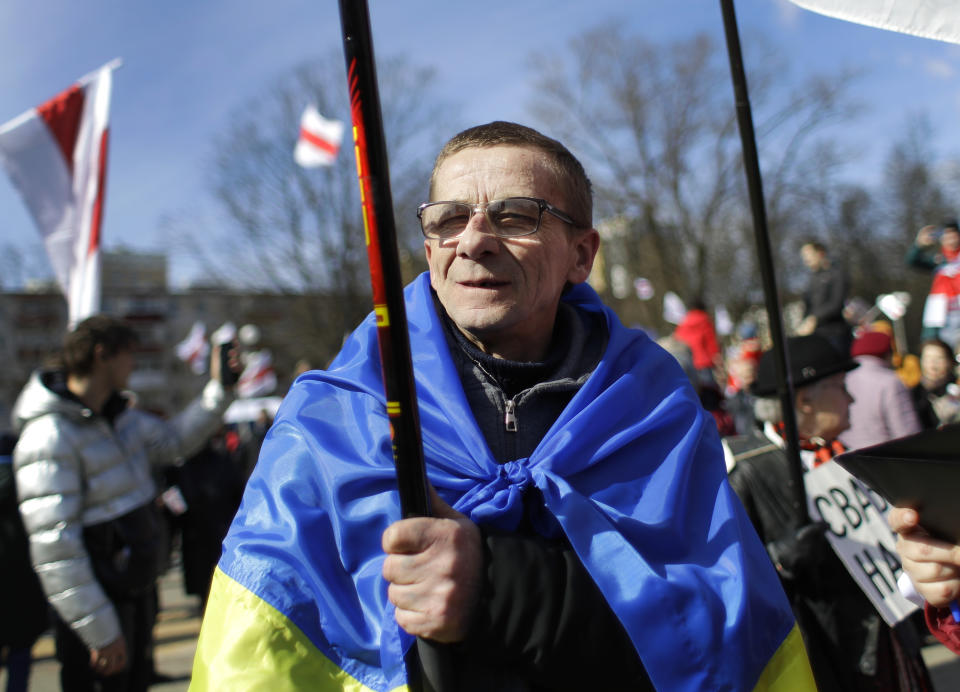 Covered by Ukrainian state flag a man takes part in celebration in Minsk, Belarus, Sunday, March 24, 2019, on the eve of March 25, a traditional day of demonstration for the opposition. Many people gather to mark what they call Freedom Day, on the 101st anniversary of the 1918 declaration of the first, short-lived independent Belarus state, the Belarusian People's Republic lasted until 1919. (AP Photo/Sergei Grits)