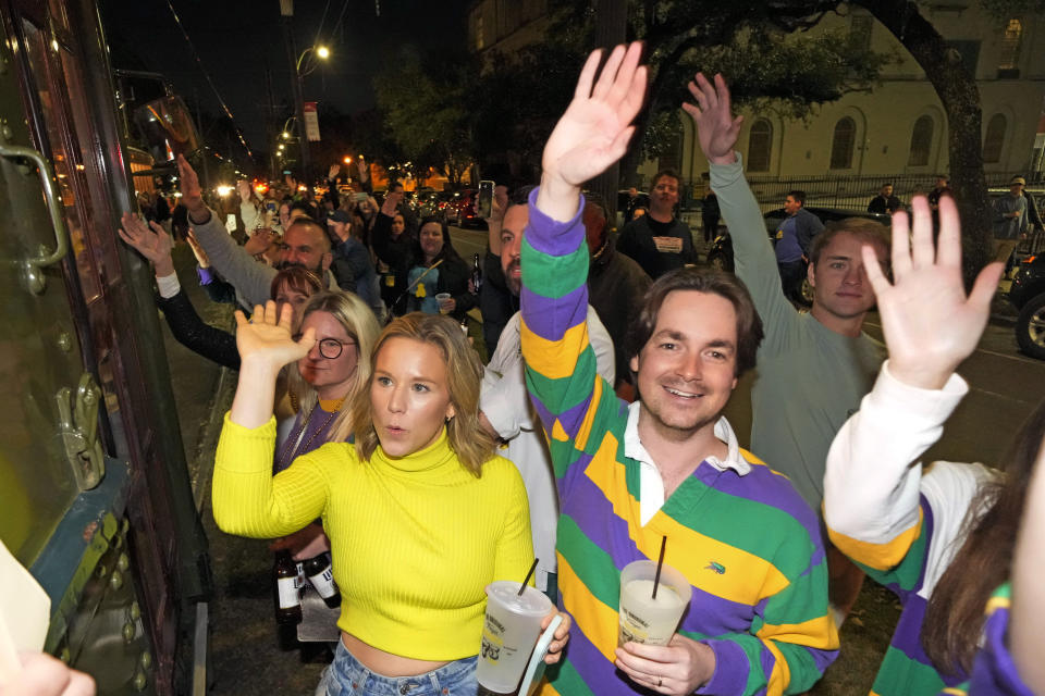 People on the street cheer as members of the Mardi Gras group The Phunny Phorty Phellows ride by reveling on a street car for their annual kick off of the Mardi Gras season on Twelfth Night in New Orleans, Friday, Jan. 6, 2023. (AP Photo/Gerald Herbert)