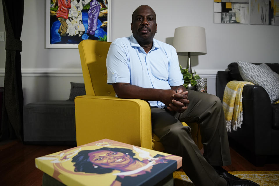 Malcolm Graham sits near a painting of his late sister, Cynthia Graham-Hurd, on Wednesday, July 15, 2020, in Charlotte, N.C. Graham, a former state senator in North Carolina, firmly believes that America's failure to confront white supremacism cost the life of his older sister, Cynthia Graham-Hurd. She was among the nine killed by Dylann Roof in 2015 during a Bible study meeting at Mother Emanuel AME Church in Charleston, S.C. (AP Photo/Chris Carlson)