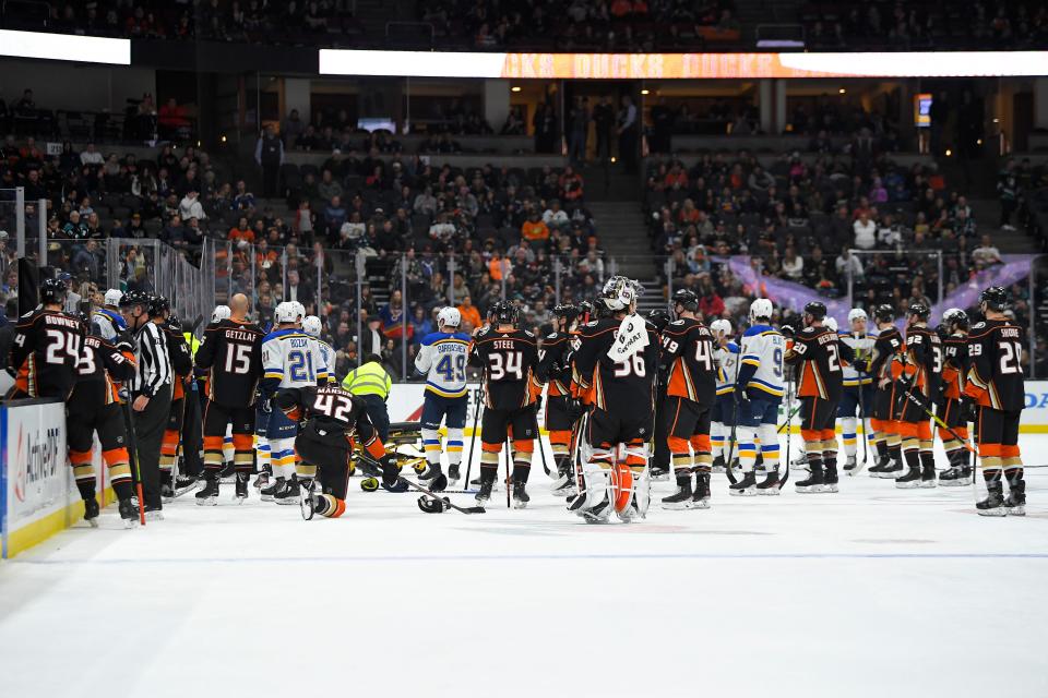 Members of the St. Louis Blues and Anaheim Ducks gather on the ice as Blues defenseman Jay Bouwmeester, who suffered a medical emergency, is worked on by medical personnel during the first period of an NHL hockey game Tuesday, Feb. 11, 2020, in Anaheim, Calif. (AP Photo/Mark J. Terrill)