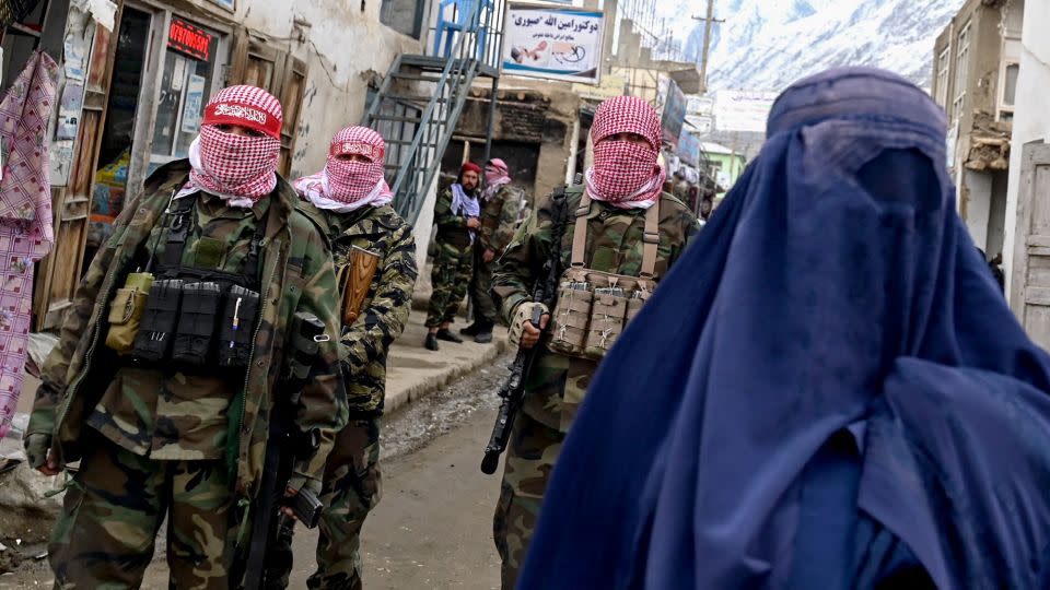 Taliban guards stand beside a burqa-clad woman on a street at a market in the Baharak district of Badakhshan province, Afghanistan on February 26, 2024. - Wakil Kohsar/AFP/Getty Images