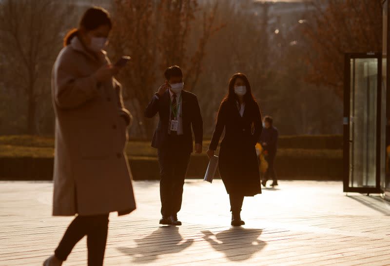 Office workers face masks outside an office complex in Beijing as the country is hit by an outbreak of the novel coronavirus