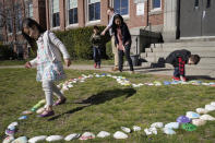 Sofia Horrigan, 4, of Quincy, Mass., left, examines a heart made of seashells with family members, from behind left, Conor, 8, John Horrigan, his wife Kim, and their son William, 3, right, while gathered for a photograph, Tuesday, April 13, 2021, at the school, in Quincy. Kim said she and her husband have struggled all year with their decision to keep their 8-year-old son in remote learning due to the coronavirus pandemic. (AP Photo/Steven Senne)