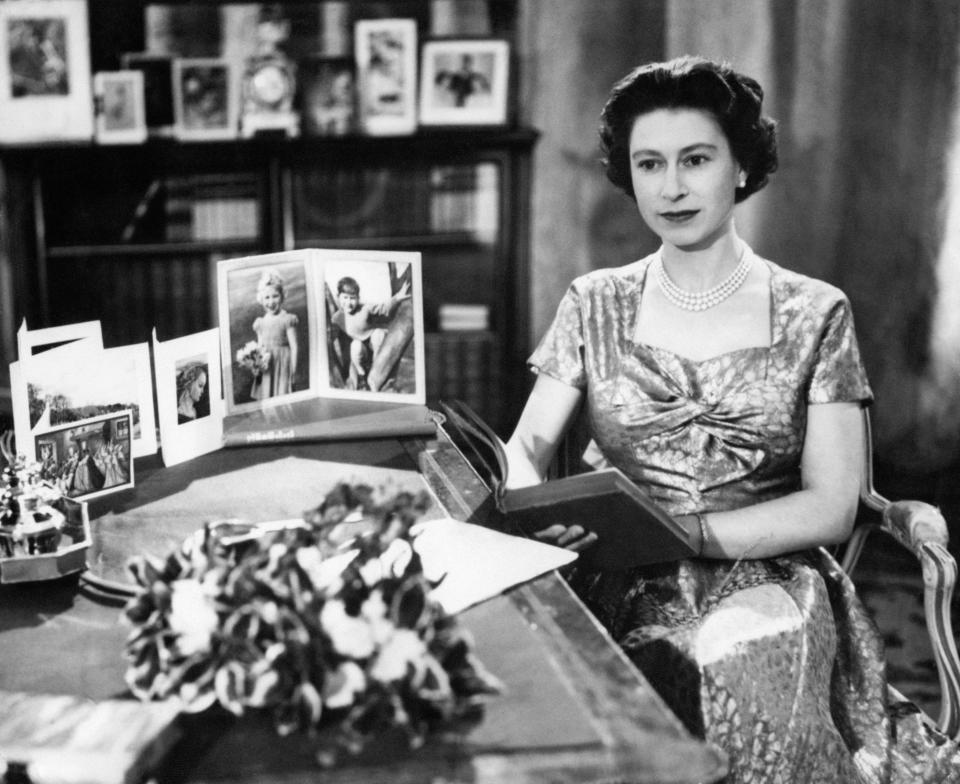 The Queen, in a gold lame dress, is seen in the Long Library at Sandringham shortly after making the traditional Christmas Day broadcast to the nation. On the desk are portraits of Prince Charles and Princess Anne. The Queen is holding the copy of 'Pilgrim's Progress', from which she read a few lines during her message. The broadcast was televised this year for the first time and was carried by both the BBC and ITV. It was the 25th anniversary of the first radio message to the Commonwealth by her grandfather, King George V.   (Photo by PA Images via Getty Images)