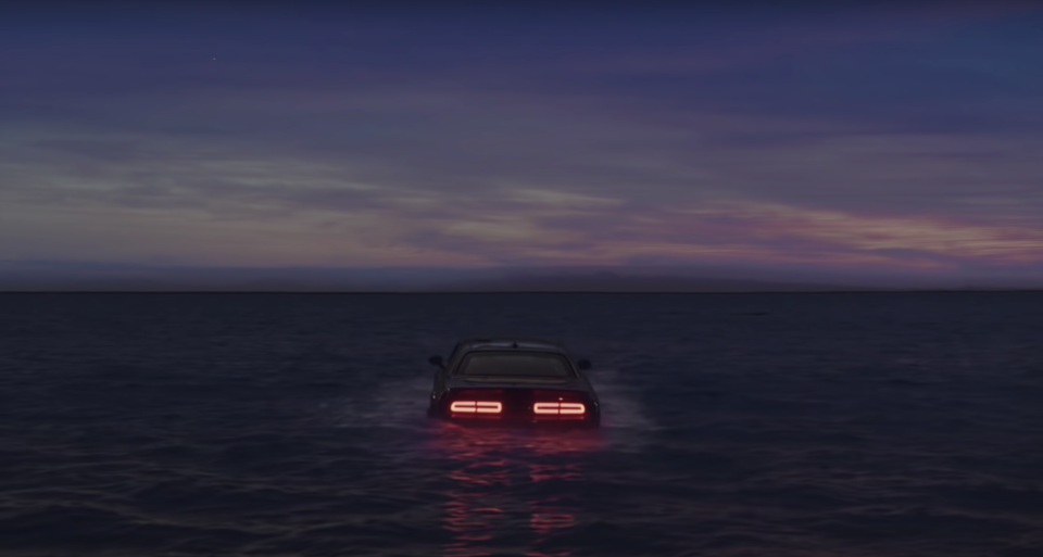 A car with its tail lights on floats before it sinks in the ocean in Billie Eilish's music video for "Everything I Wanted"