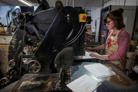 Lottie Small use the die stamping press at the workshop of Barnard and Westwood, who are printing the invitations for Britain's Prince Harry and Meghan Markle's wedding at Windsor Castle in May, London, Britain, March 22, 2018. Victoria Jones/Pool via Reuters