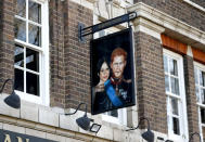 A sign depicting the image of Britain's Prince Harry and his wife Meghan, hangs outside the Duke of Sussex pub near Waterloo station, London, Tuesday March 9, 2021. Prince Harry and Meghan's explosive TV interview has divided people around the world, rocking an institution that is struggling to modernize with claims of racism and callousness toward a woman struggling with suicidal thoughts. (AP Photo/Frank Augstein)