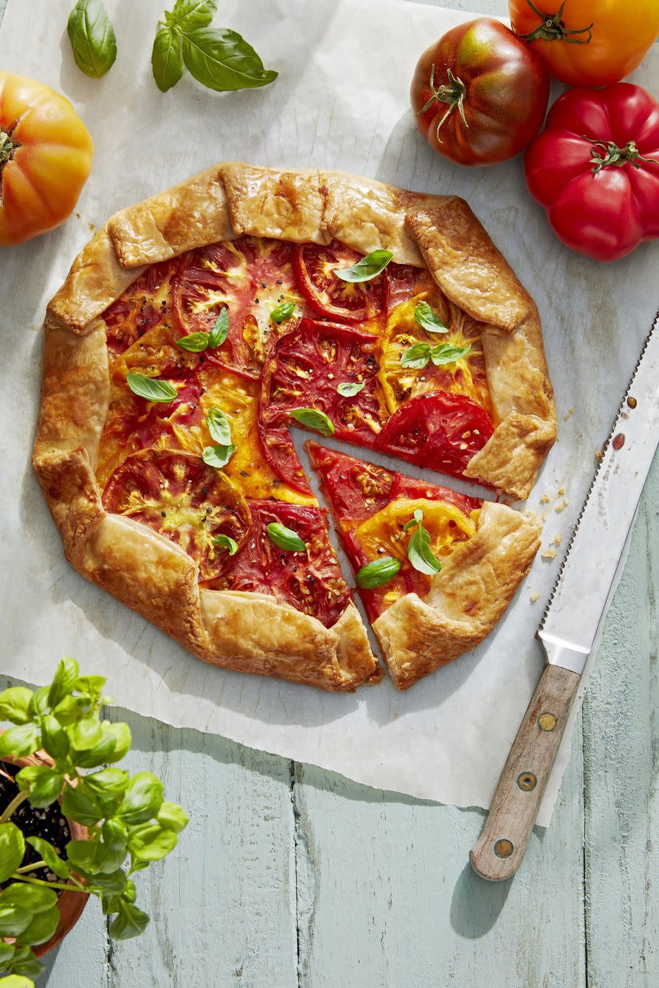 rustic tomato galette on a sheet of parchment paper with a slice cut