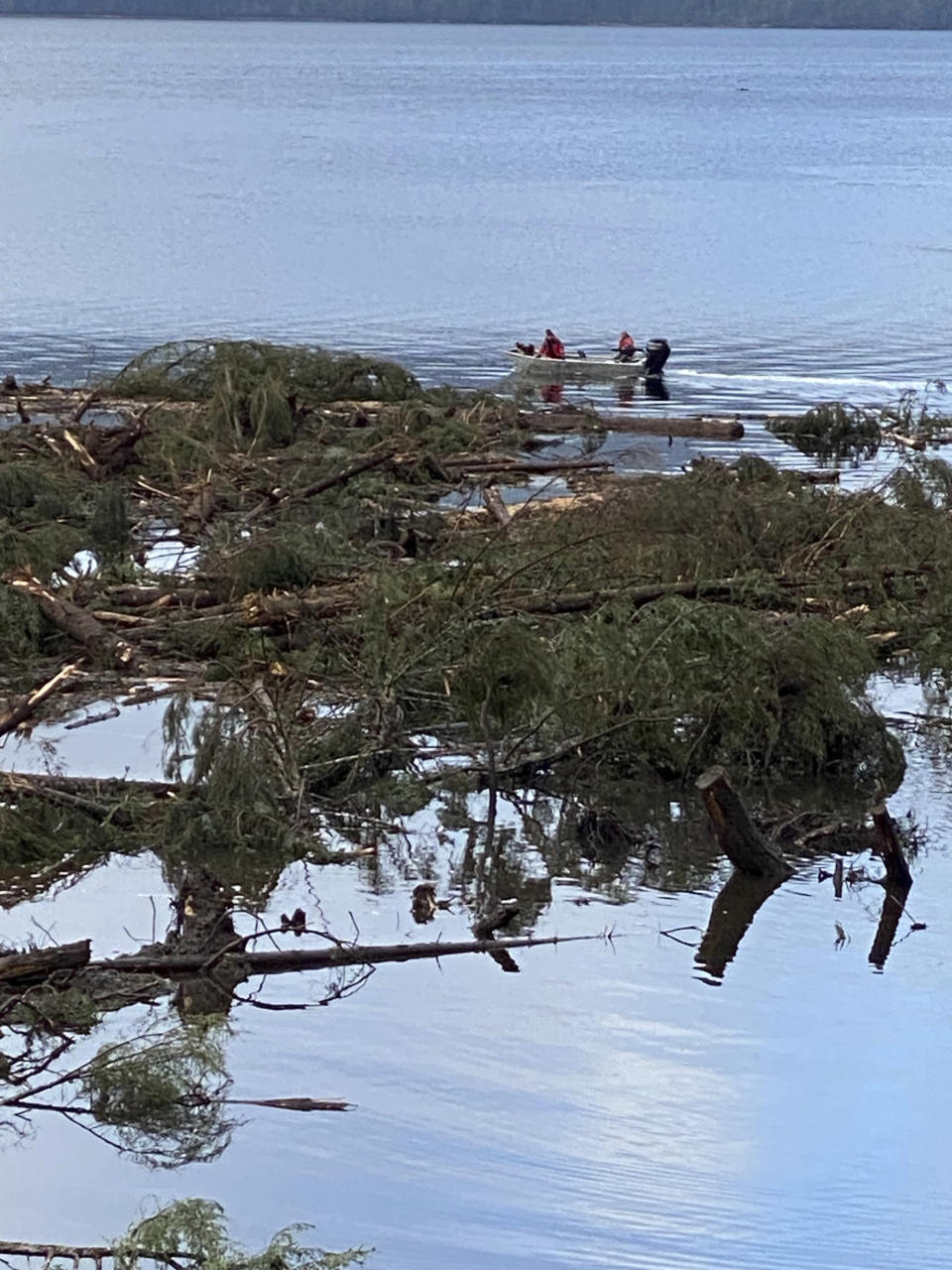 This photo provided by the Alaska Department of Public Safety shows boat operators patrolling the waters near a massive landslide that extends into the sea at mile 11 of the Zimovia Highway, Wednesday, Nov. 22, 2023, in Wrangell, Alaska. Search and rescue operations have been ongoing since the incident was reported earlier in the week. Three people have died and searchers looked Wednesday for three others who remain missing after a landslide ripped through a remote Alaska fishing community on Monday, Nov. 20, 2023. (Alaska Department of Public Safety via AP)