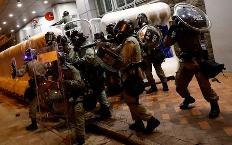 Riot police hold their shields outside Monk Kok police station in Hong Kong - Credit: Kai Pfaffenbach/Reuters