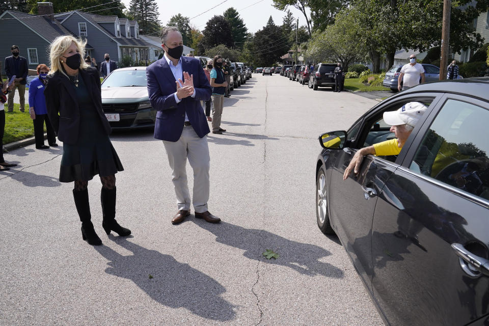 Jill Biden, left, wife of Democratic presidential candidate former vice president Joe Biden, and Doug Emhoff, center, husband of Democratic vice presidential candidate Sen. Kamala Harris, D-Calif., greet a supporter in a passing car during a campaign stop, Wednesday, Sept. 16, 2020, in Manchester, N.H. (AP Photo/Steven Senne)