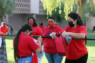 Volunteers and members of the Phoenix Indian Center hang up red skirts designed by artists to raise awareness for missing and murdered Indigenous women and girls, at Arizona State Capitol in Phoenix, Wednesday, May 5, 2021. Phoenix Indian Center Executive Director Patricia Hibbeler said the skirts are a huge part of Native American women and girls' lives. (AP Photo/Cheyanne Mumphrey)