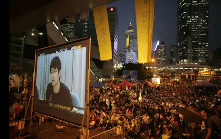 Pro-democracy protestors watch formal talks between student protest leaders and city officials on a video screen near the government headquarters in Hong Kong October 21, 2014. REUTERS/Carlos Barria