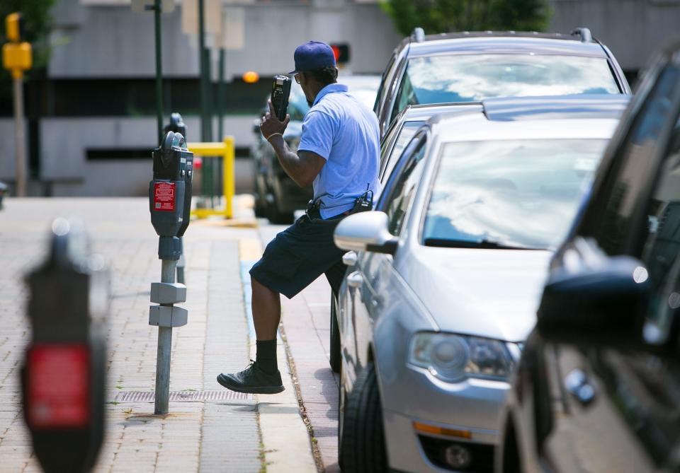 A parking enforcement officer checks meters along North French Street in Wilmington in 2016. Mayor Mike Purzycki's administration says they are conducting a parking study this year, 2024, to evaluate on-street, time limited parking space and make recommendations for improvement.