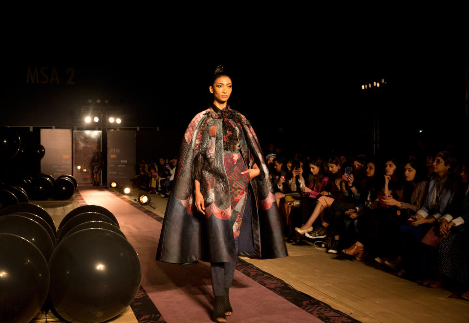 <p>Das Designer-Duo Pankaj und Nidhi macht Mode für mutige und selbstbewusste Fashionistas. Bei der Kombination aus einem auffälligem Cape, einer Rüschenbluse und gemusterter Hose sind Blicke garantiert. (Bild: AP Photo) </p>