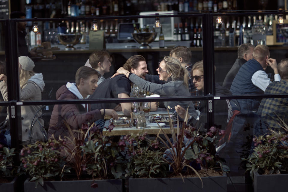 FILE - In this Saturday, April 4, 2020 file photo a couple hug and laugh as they have lunch in a restaurant in Stockholm, Sweden. (AP Photo/Andres Kudacki, File)