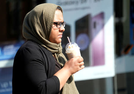 A woman carries a drink with a straw from a McDonalds restaurant in Loughborough, Britain April 19, 2018. REUTERS/Darren Staples