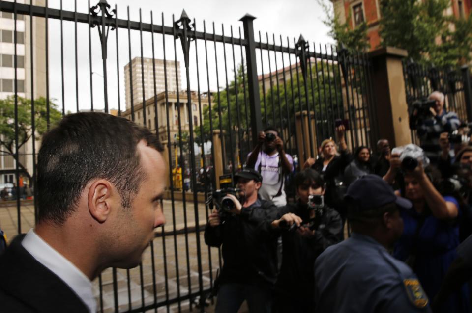 Members of the media wait to photograph Olympic and Paralympic track star Oscar Pistorius (L) as he leaves after his trial at the North Gauteng High Court in Pretoria March 4, 2014. Pistorius is on trial for murdering his girlfriend Reeva Steenkamp at his suburban Pretoria home on Valentine's Day last year. He says he mistook her for an intruder. REUTERS/Siphiwe Sibeko (SOUTH AFRICA - Tags: CRIME LAW SPORT ATHLETICS)