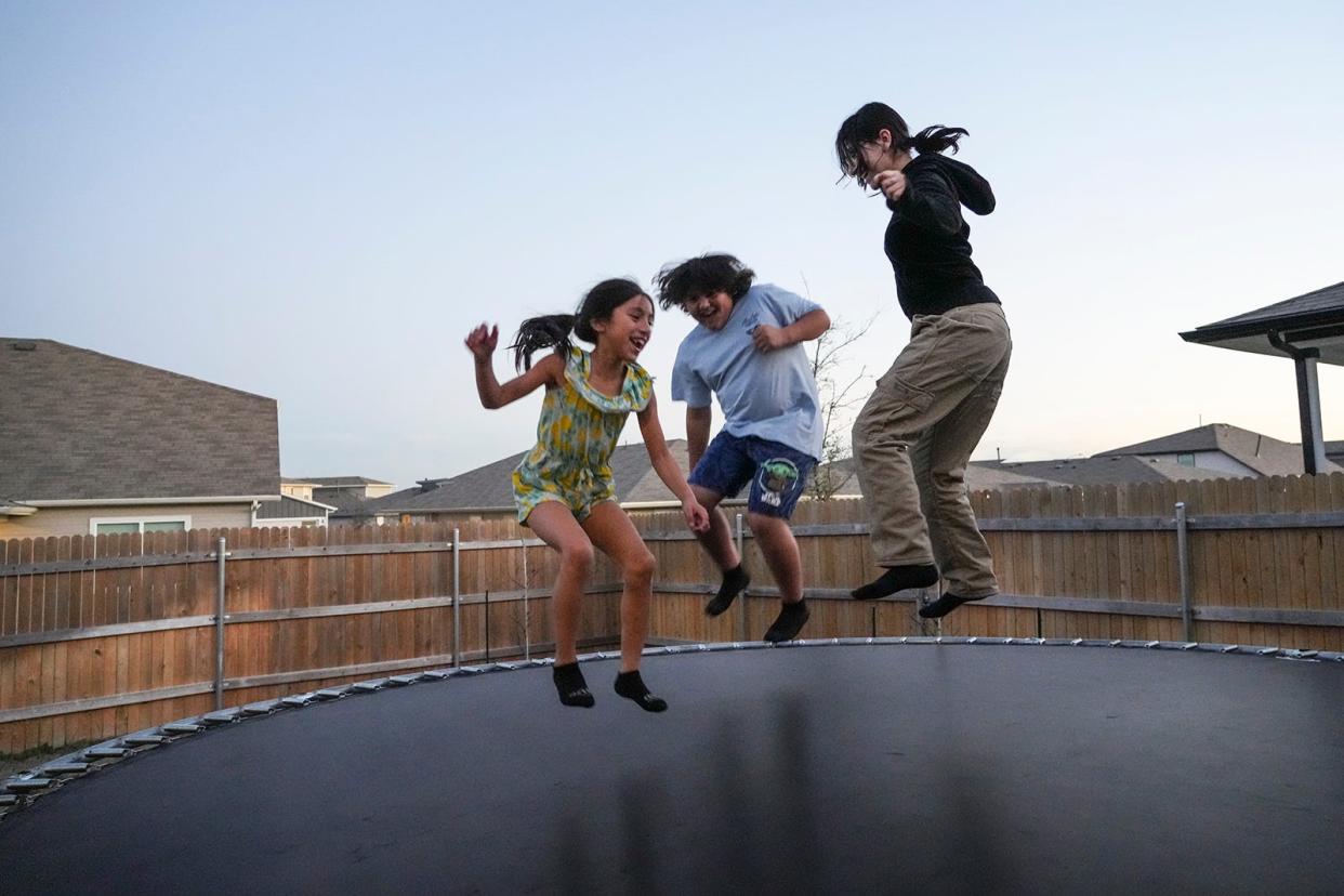 From left, Neome Parra-Betancurt, Jose Parra-Betancurt and Nancy Parra-Betancurt jump on the trampoline in their new backyard Wednesday. With help from Season for Caring, the family moved into their first home last month.