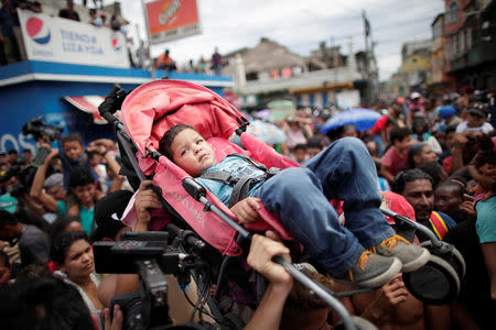 Honduran migrants, part of a caravan trying to reach the U.S., hold up a child in a stroll while, gathering at the Guatemalan border to cross into Mexico, in Tecun Uman, Guatemala October 19, 2018. REUTERS/Ueslei Marcelino