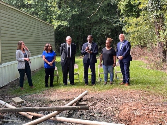 Activist Catherine Coleman Flowers,  USDA Secretary Tom Vilsack, EPA Administrator Michael Regan, Lowndes resident Aquilla Grant and White House Infrastructure Coordinator Mitch Landrieu stand behind a pool of raw sewage in Grant's backyard.