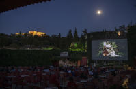 In this Thursday June 4 , 2020 photo people watch a trailer for the 2019 movie "Pinocchio" at the Thisio outdoor summer cinema as the Ancient Acropolis is seen lit up in the background. Cine Thision is one of the oldest open-air movie theaters in Athens, built in 1935. (AP Photo/Petros Giannakouris)