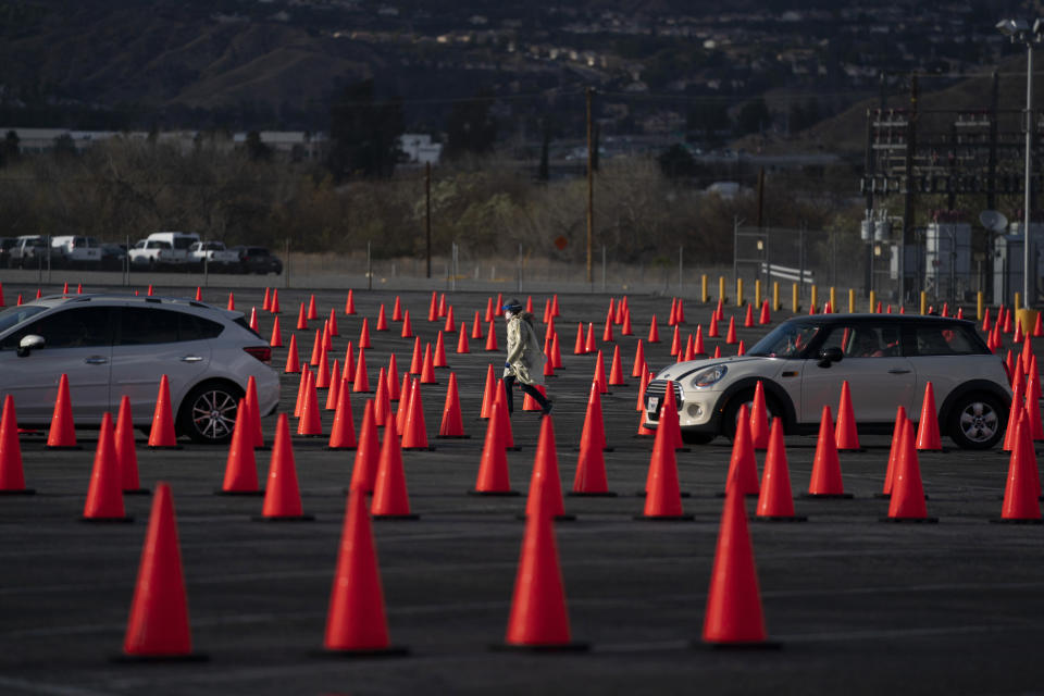 FILE - In this Jan. 22, 2021 file photo medical staff members walk between traffic cones at a mass COVID-19 vaccination site set up in the parking lot of Six Flags Magic Mountain in Valencia, Calif. Five weeks into its vaccination program, California still doesn't have nearly the supply to meet demand and there's growing angst among residents over the difficulty to even get in line for a shot. Social media is awash with people seeking or giving tips on how to maneuver through the system. (AP Photo/Jae C. Hong,File)