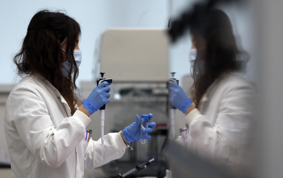 A lab assistant uses a pipette to prepare Coronavirus RNA for sequencing at the Wellcome Sanger Institute that is operated by Genome Research in Cambridge, Thursday, March 4, 2021. Cambridge University microbiologist Sharon Peacock understood that genomic sequencing would be crucial in tracking the coronavirus, controlling outbreaks and developing vaccines, so she began working with colleagues around the country to put together a plan when there were just 84 confirmed cases in the country. The initiative helped make Britain a world leader in rapidly analyzing the genetic material from large numbers of COVID-19 infections, generating more than 40% of the genomic sequences identified to date.(AP Photo/Frank Augstein)