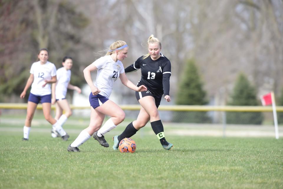 Algonac's Natalie Boulier (21) attempts to dribble past Almont's McKenna Castillo (13) during Algonac's 5-1 win at Orchard Primary School in Almont on Wednesday, April 20, 2022.