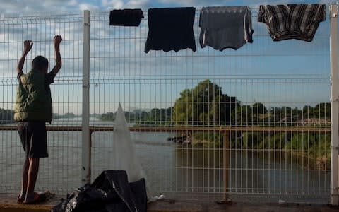 A Honduran migrant looks over the Suchiate River that separates Mexico from Guatemala - Credit: AP Photo/Oliver de Ros